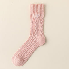 Pink crew sock with twisted cable knit columns, a straight ribbed cuff and a small tonal embroidered bow