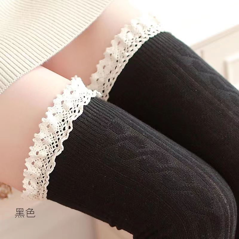 Black long socks with cable-like knit texture and contrasting pale lace cuffs, close-up