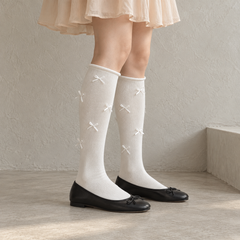 AI styling illustration of white scattered ribbon-bow long socks with black ballet flats beside a warm-gray wall