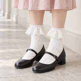 AI styling illustration of White raised-floral socks with broad lace flounces, black Mary Jane shoes and a pale pink skirt in a stone corridor