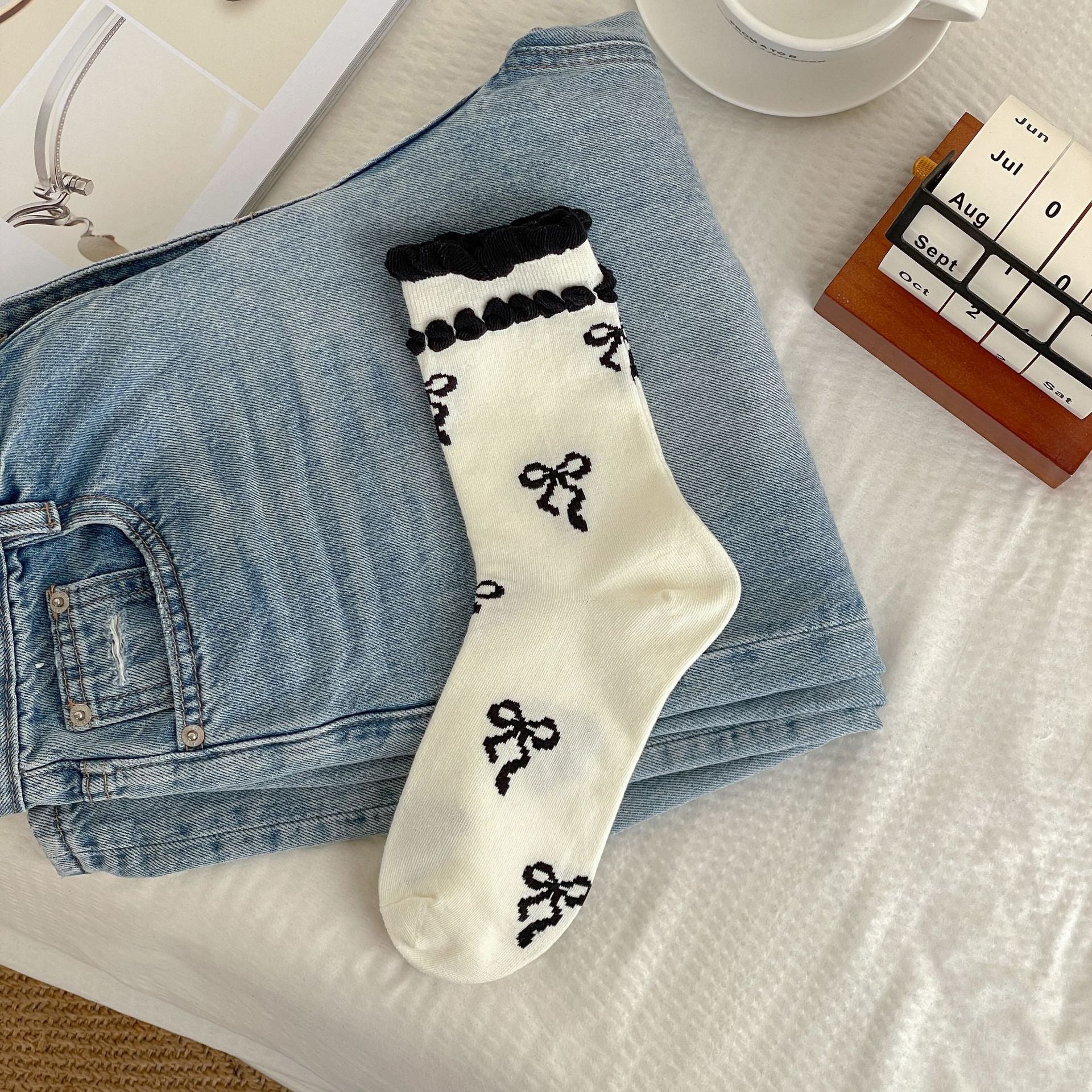 Cream sock body with black bow motifs and two rows of black raised cuff trim