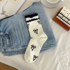 Cream sock body with black bow motifs and two rows of black raised cuff trim