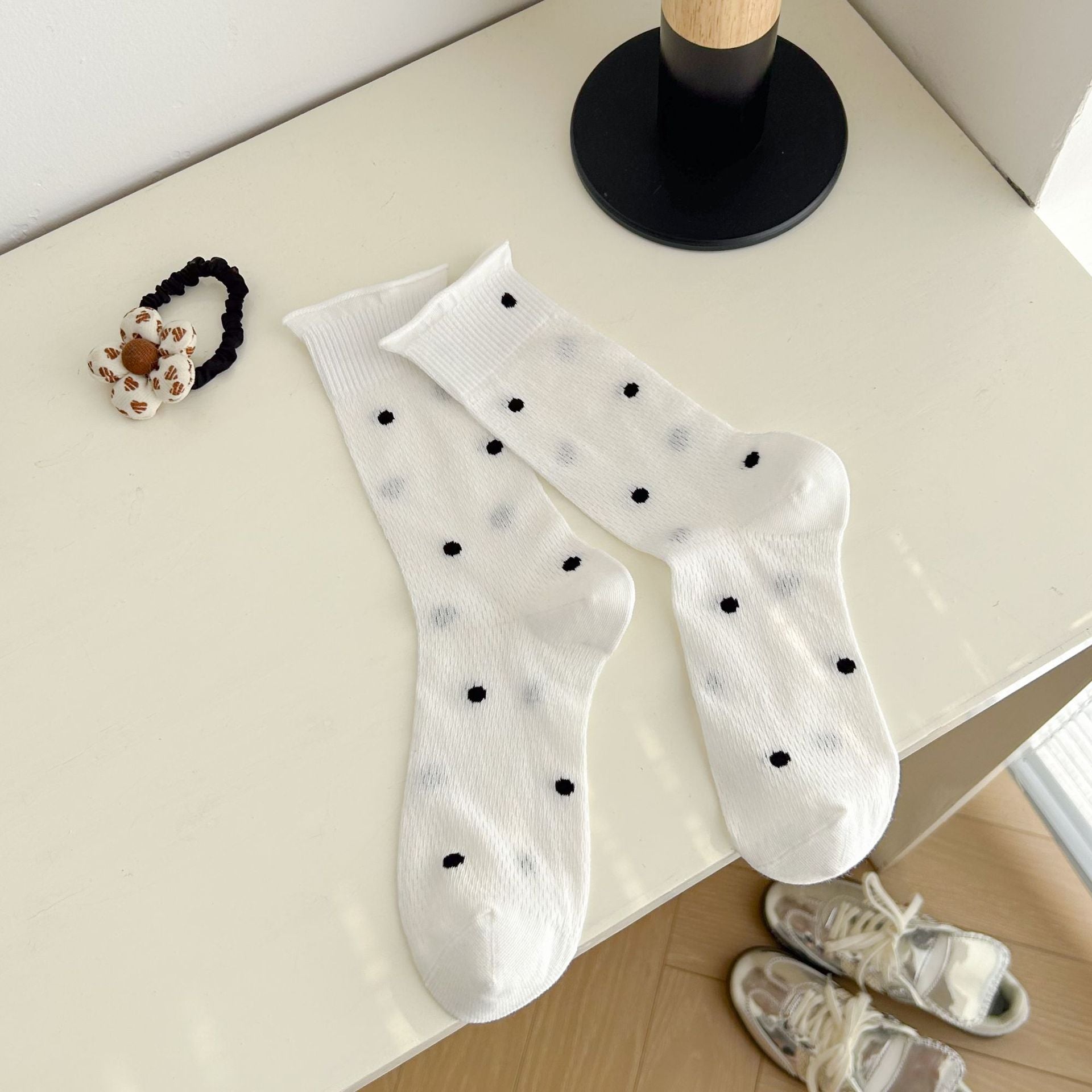 White knitted socks with small black dots and rolled cuff edges, displayed as a pair