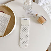 Milk White polka dot sock with dark dots and a broad ribbed cuff, laid flat