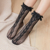 Black floral mesh lace socks worn on feet, showing patterned mesh and ruffled lace cuffs