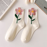 White crew socks with pink open flowers forming the cuff edges and green leafy stems