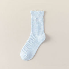 Light Blue ribbed crew sock with a scalloped cuff and heart-bow embroidery on a beige background