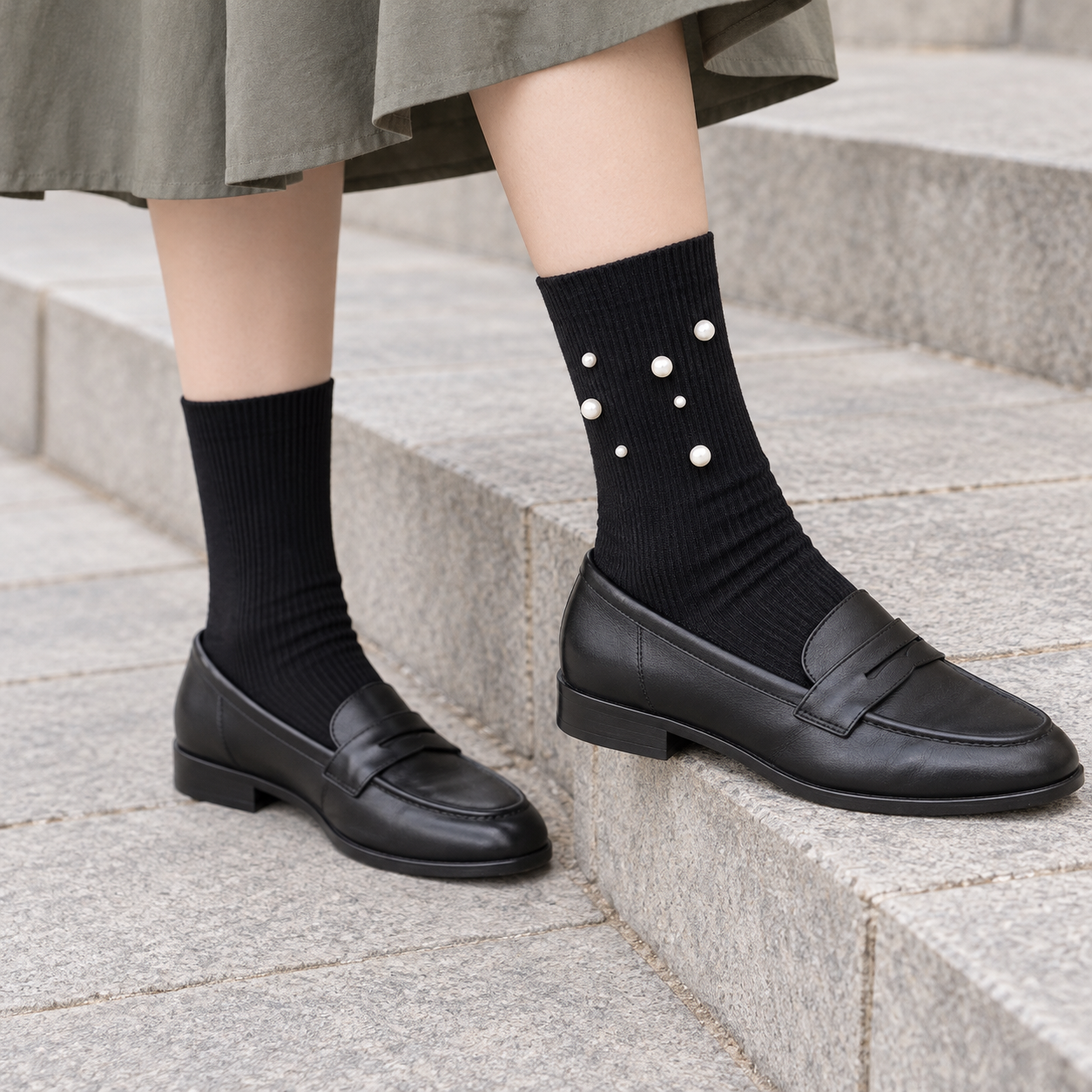 AI styling illustration of Black fine-rib socks with a seven-bead outer cluster, worn with charcoal loafers on gray stone steps.