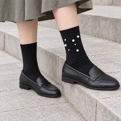 AI styling illustration of Black fine-rib socks with a seven-bead outer cluster, worn with charcoal loafers on gray stone steps.