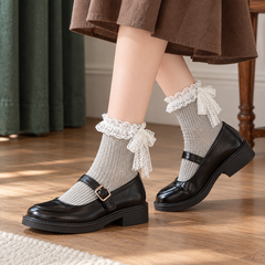 AI styling illustration of Gray fine-rib socks with White lace bows and tails, black buckle shoes and a brown skirt before a green curtain.