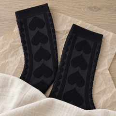 AI flat-lay illustration of two Black heart-knit sock shafts with ribbed cuffs and lower ends concealed.