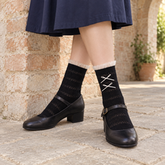 AI styling illustration of Black striped-knit socks with tulle cuffs and narrow off-white bows, worn with black Mary Janes beside a brick arch.