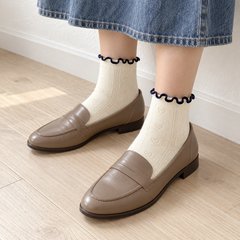 AI styling illustration of Cream heart-pointelle socks with taupe loafers beside a white wall.