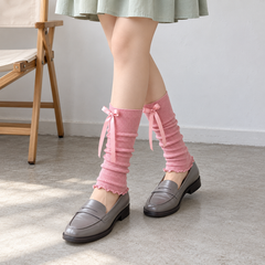 AI styling illustration of Pink ribbon footless leg warmers with gray loafers and a mint skirt beside a canvas chair.