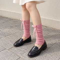 AI standing styling illustration of Pink ribbed footless leg warmers with black loafers and a cream skirt.