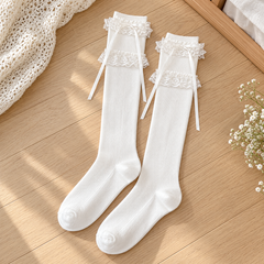 AI flat product illustration of two White long ribbed socks with separated lace bands and narrow upper ribbon tails on pale oak.