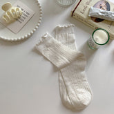 White socks with vertical leaf-like openwork and lightly ruffled cuffs, displayed as a pair