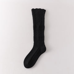 Black long sock with repeated leaf pointelle sections and two broad horizontal textured bands