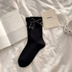 Black crew socks with straight cuffs and broad light-edged bows with small dot accents