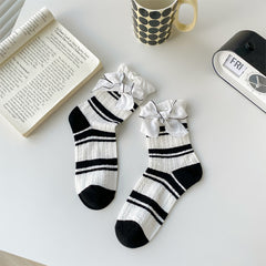 White textured socks with black stripes, black toes and white bows edged in black