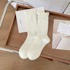 White ribbed socks with looped frill cuffs and pearl-style beads shown on one sock