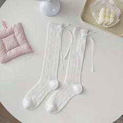 White pointelle crew socks with vertical diamond eyelet lines and long ribbon bows