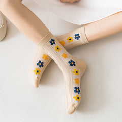 Beige cable-textured socks worn with blue, yellow and orange raised flower motifs