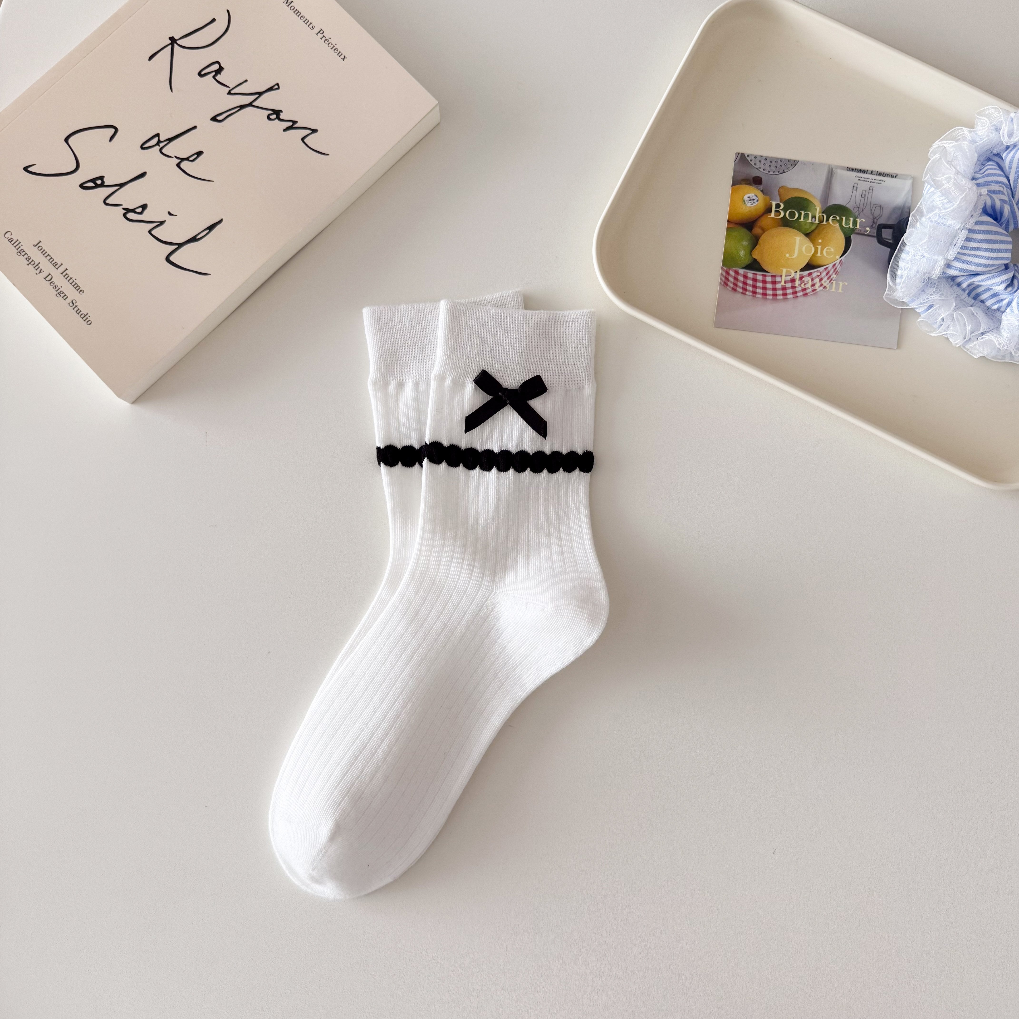 White ribbed crew socks with straight cuffs, black ribbon bows and raised black dot knit bands.