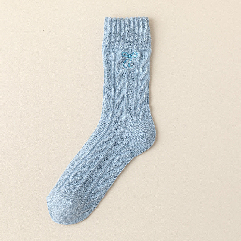 Blue crew sock with twisted cable knit columns, a straight ribbed cuff and a small blue embroidered bow