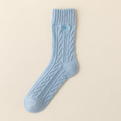Blue crew sock with twisted cable knit columns, a straight ribbed cuff and a small blue embroidered bow
