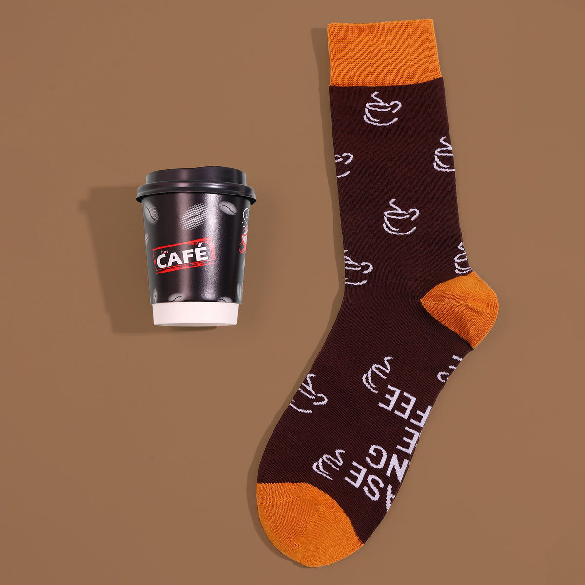 Brown coffee-cup crew sock with orange cuff, heel and toe, beside cup-shaped sock packaging