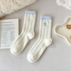Blue Trim cream crew socks with fuzzy diamond texture, blue cuffs and embroidered bow in a flat lay