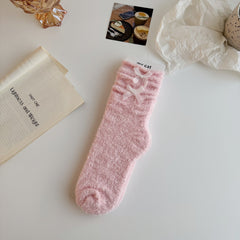 Pink textured crew socks with folded cuffs and two white ribbon bows
