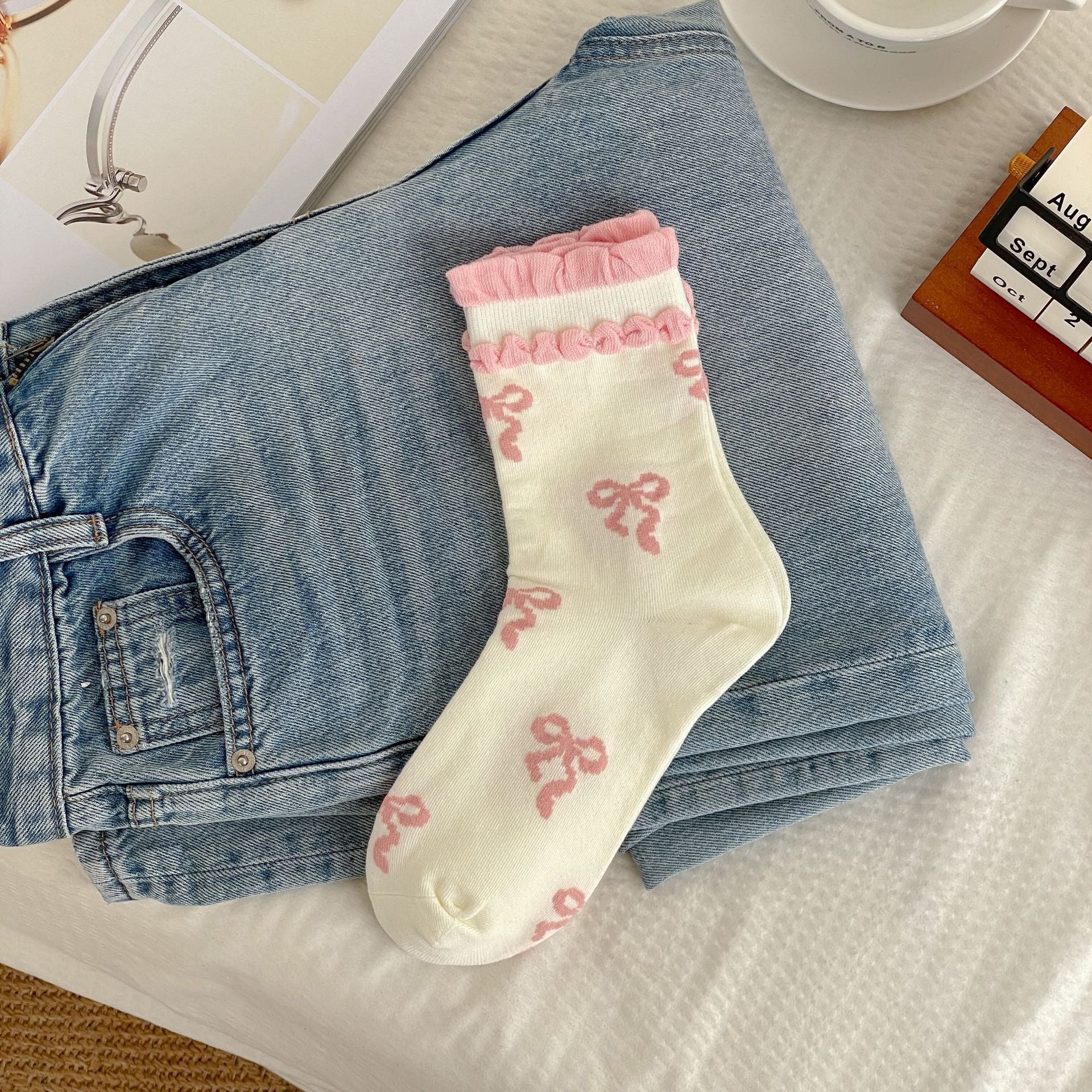 Cream sock body with pink bow motifs and two rows of pink raised cuff trim