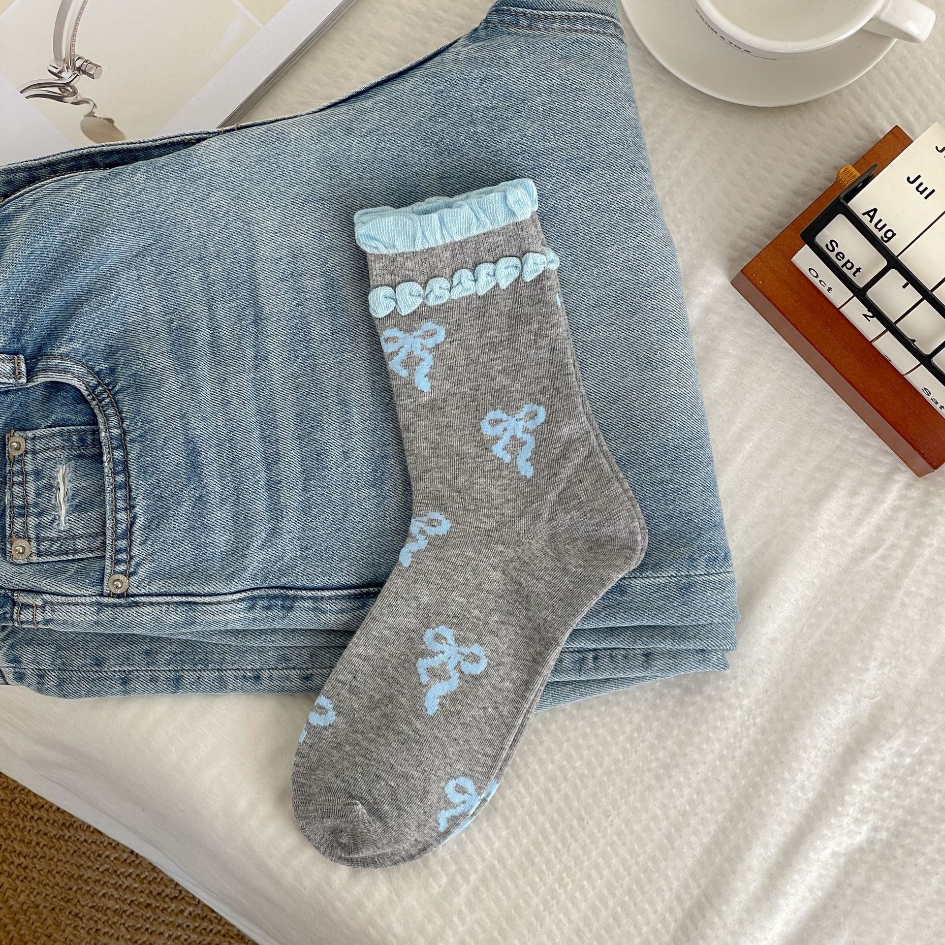Gray sock body with light blue bow motifs and two rows of light blue raised cuff trim