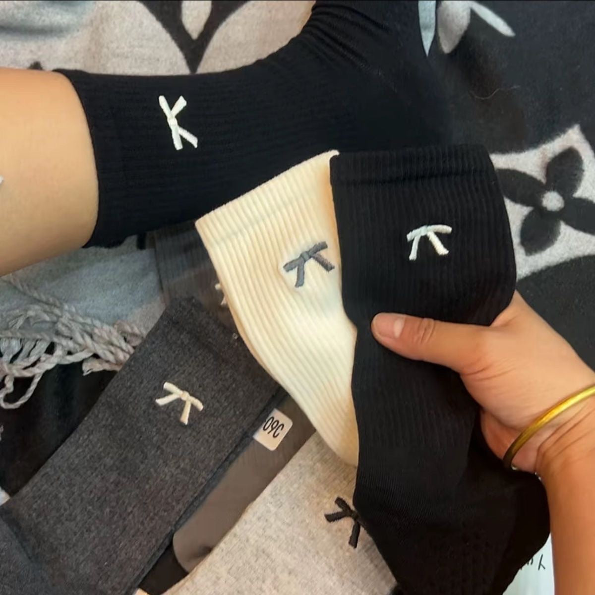Close view of tiny embroidered bows and fine vertical ribs on black, cream and gray sock colors