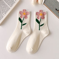 White crew socks with pink open flowers forming the cuff edges and green leafy stems