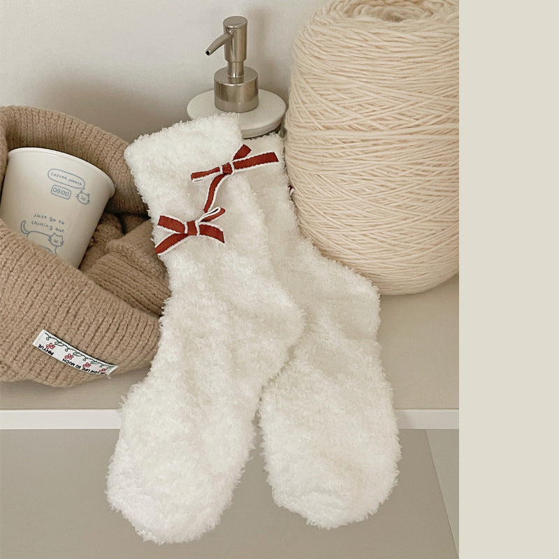White fuzzy-looking crew socks with red bows outlined in pale trim