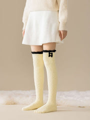 Yellow fuzzy long socks with black cuff trim and stacked black bow detail