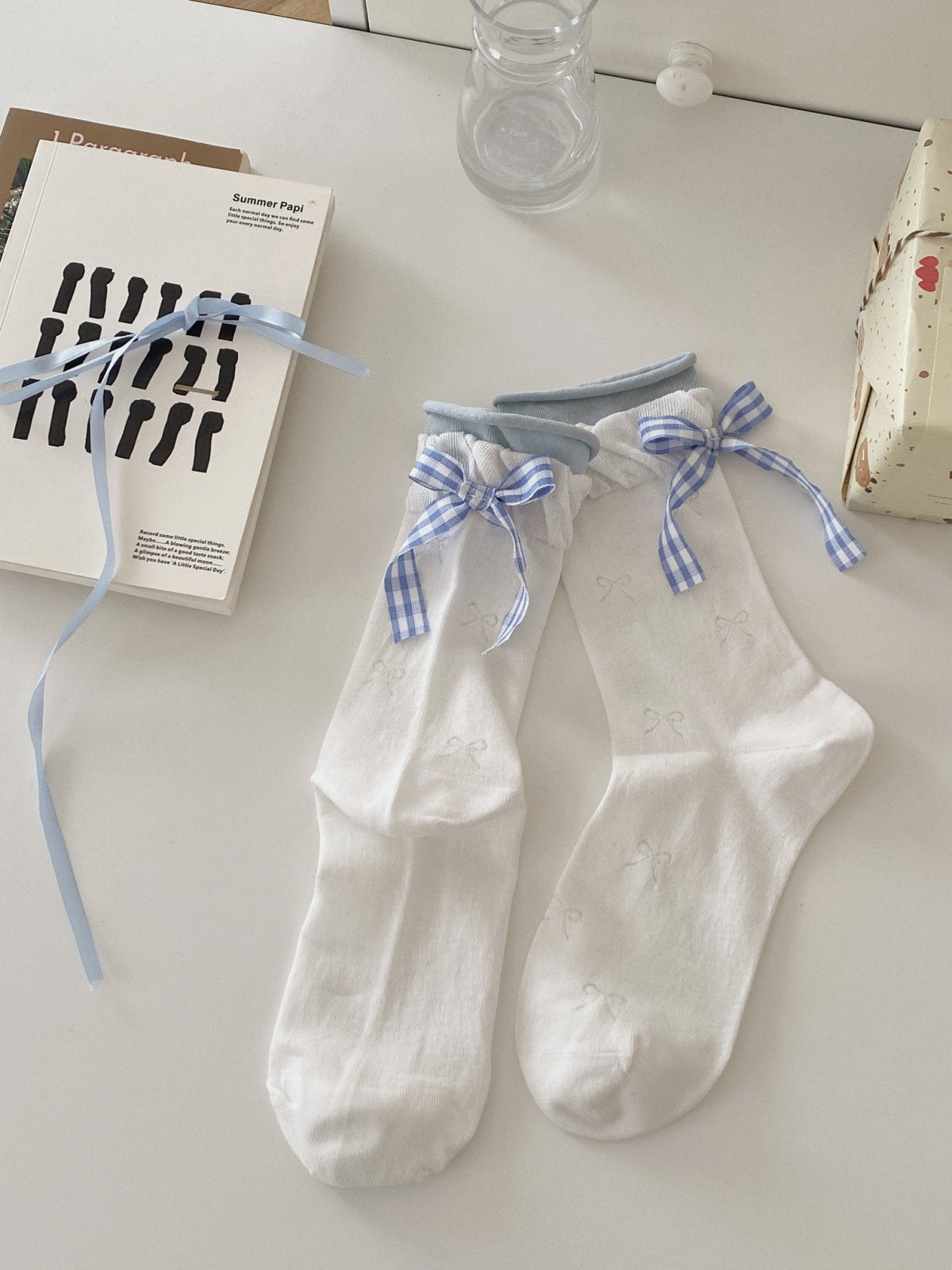 White knit ankle socks with blue gingham bow details, light blue cuffs and small bow motifs