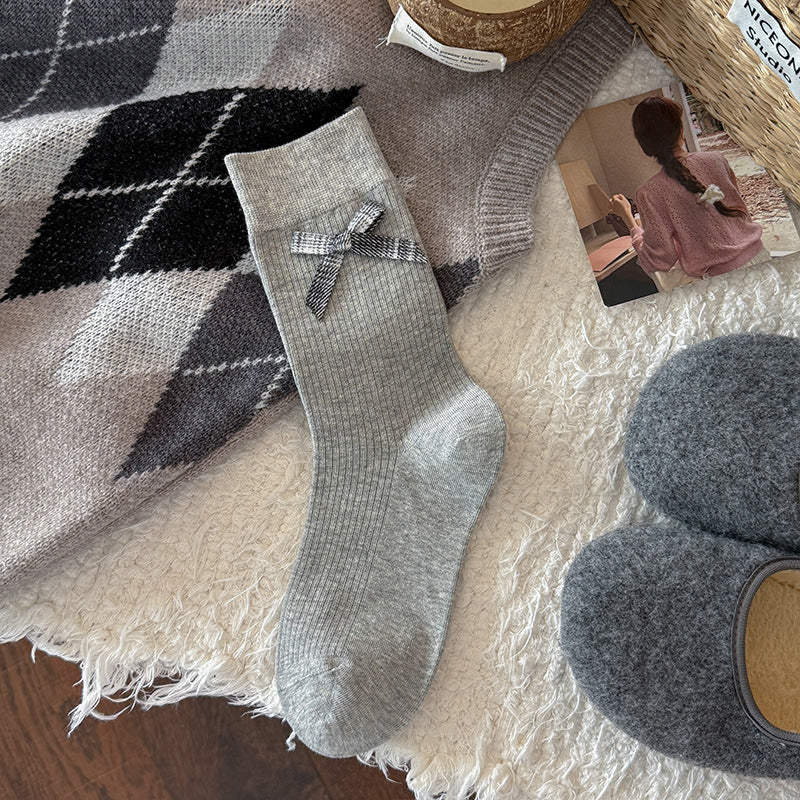 Light Gray ribbed crew sock with a gray gingham bow below the cuff, shown flat beside styling props