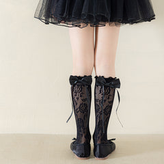 Girls' black floral lace socks with matching satin bows, styled with black shoes