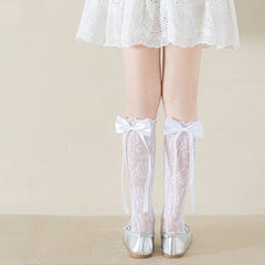 Girls' white floral lace socks with satin bows and long ribbon tails, rear view with silver flats