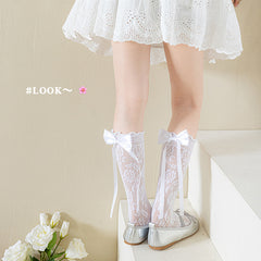 Girls' white floral lace bow socks shown from the side with a white dress and silver flats