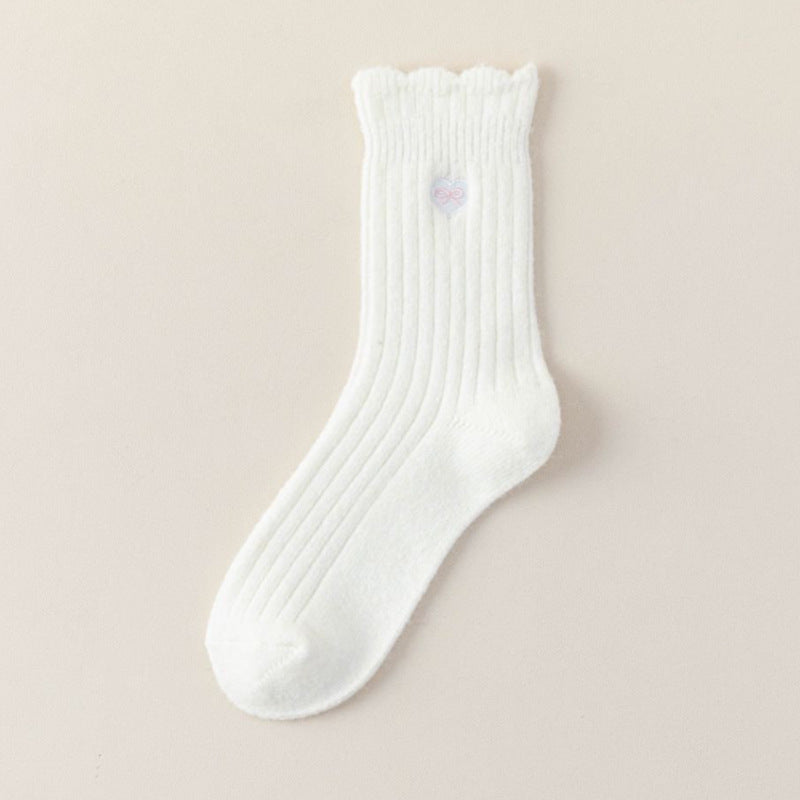 Milk White ribbed crew sock with a scalloped cuff and pastel heart-bow embroidery on a beige background