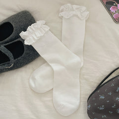 White ribbed crew socks with white heart-patterned lace cuffs, shown beside styling shoes