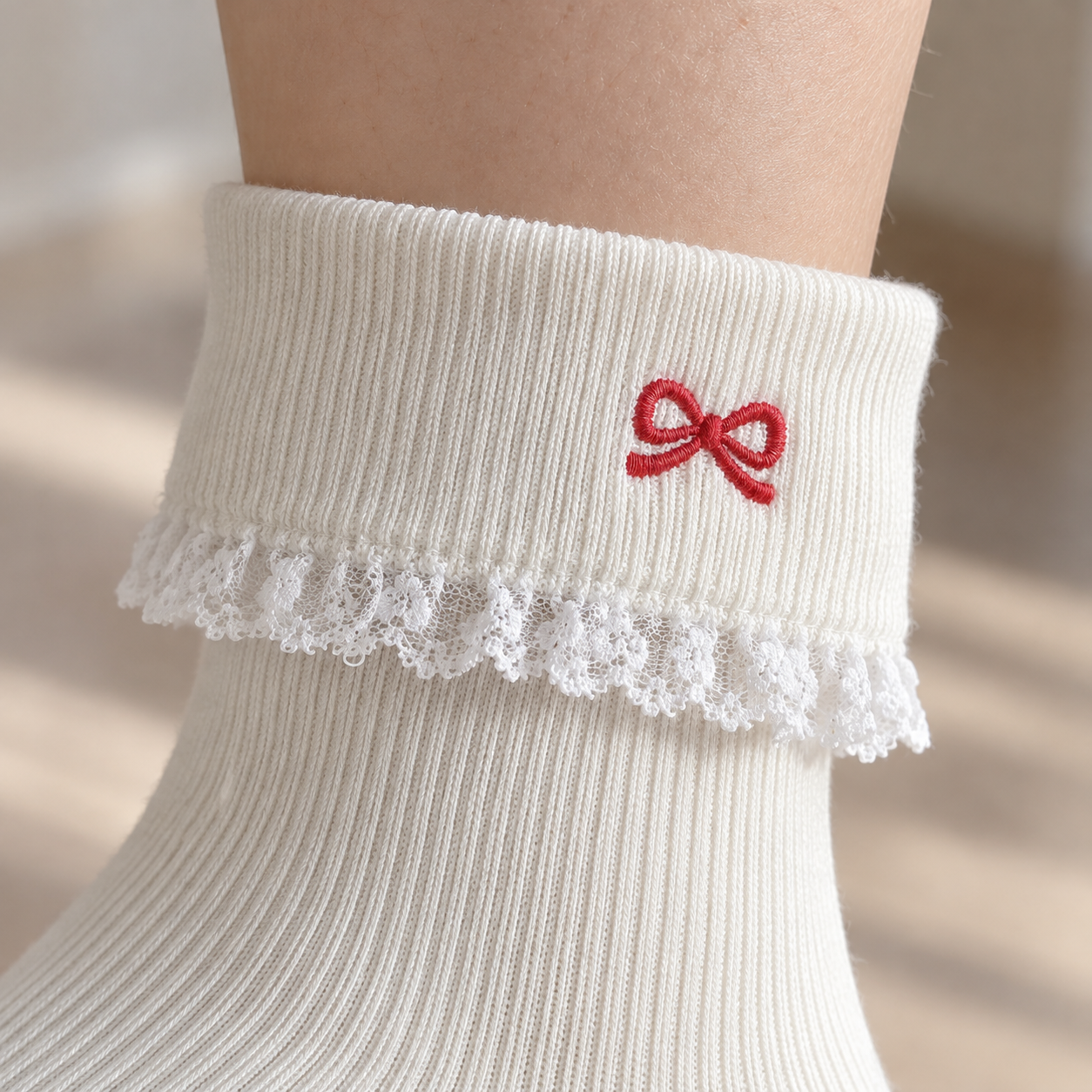 AI close illustration of a small red embroidered loop bow on a White ribbed folded cuff with a narrow lace frill below its edge
