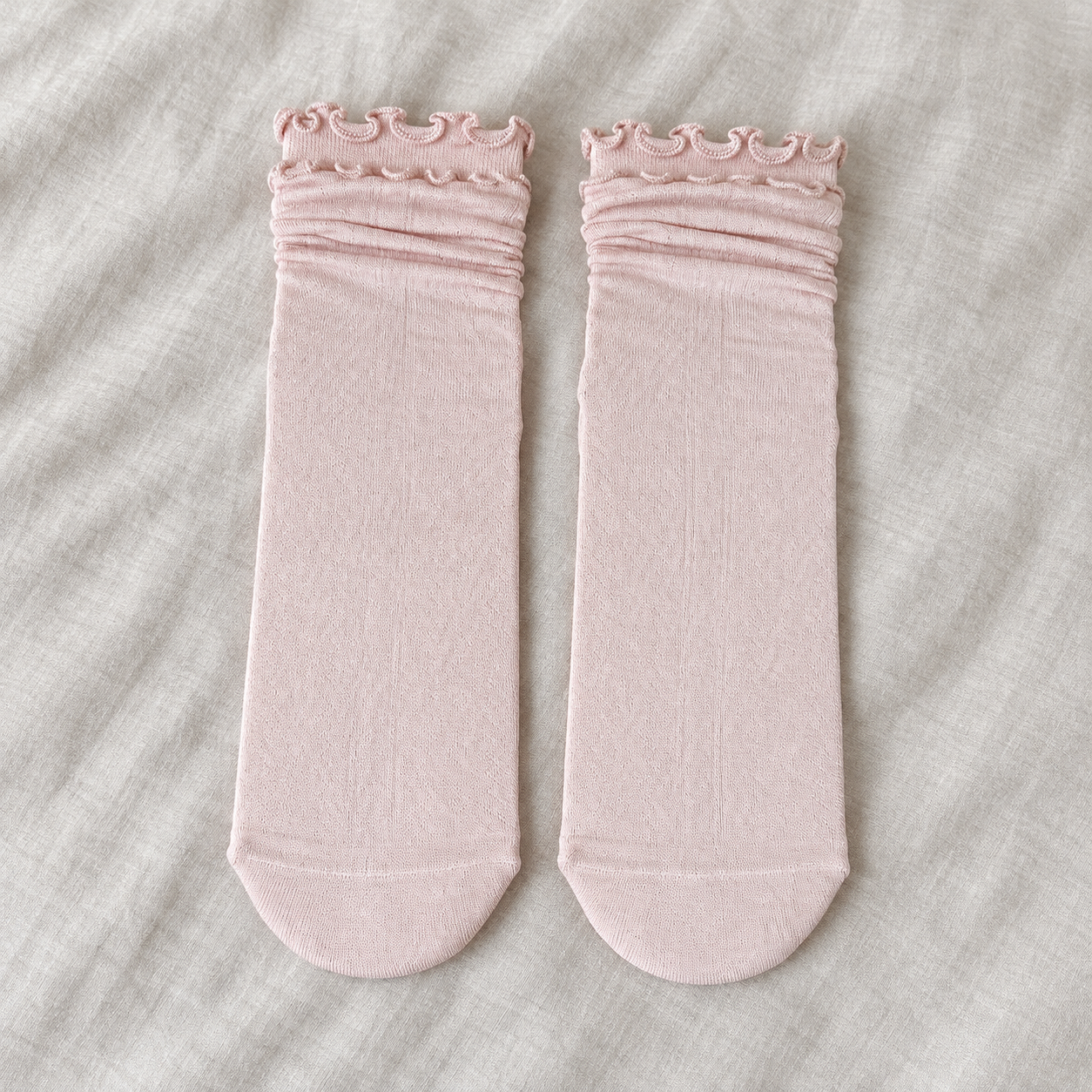 AI front-facing flatlay illustration of one Light Pink sock pair with softly rolled upper sections, waved rims and plain rounded toes
