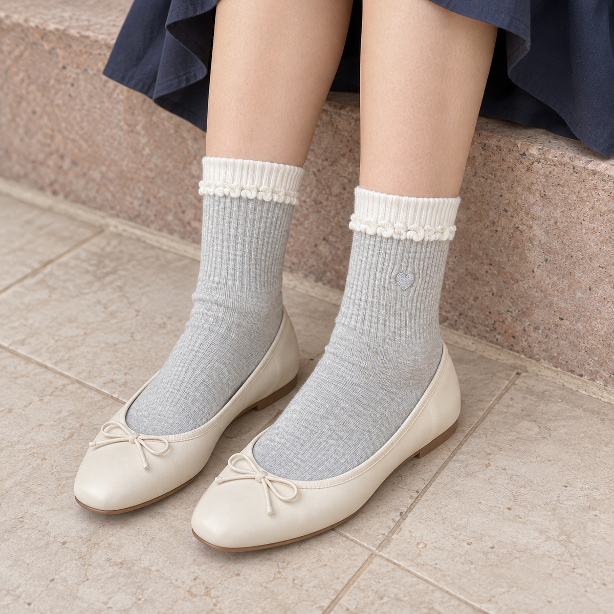 AI styling illustration of Light Gray heart socks with white ribbed bands and curled-knit trim, seated with ivory ballet flats.