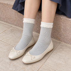 AI styling illustration of Light Gray heart socks with white ribbed bands and curled-knit trim, seated with ivory ballet flats.
